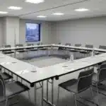 Conference room set up with commercial folding tables in U-shape configuration for hotel or event centre use